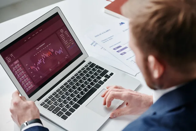 Businessman reviewing data analytics dashboard on laptop in bright office. Service standards for a customer data platform that the buyer, not the supplier, defines